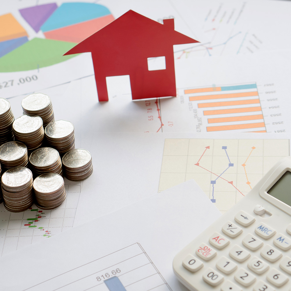 Mesa com algumas moedas, calculadora e uma casinha de papel